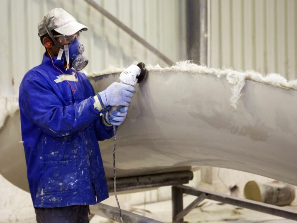 Technician sanding fiberglass surface during slide repair in MA