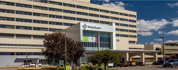 Wide shot of a large hospital building under a blue sky.