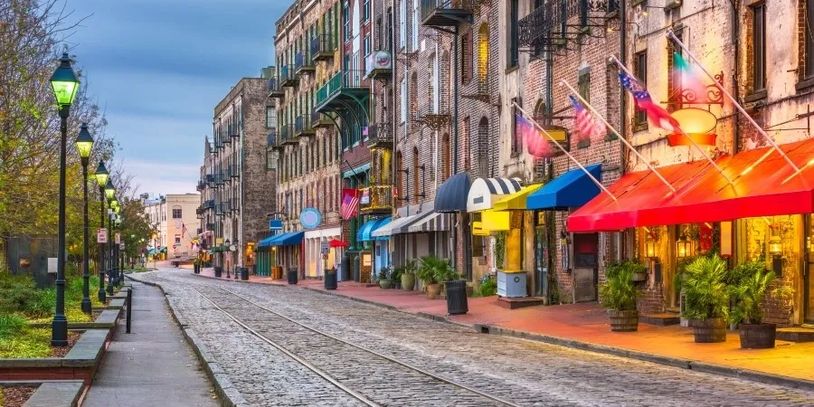 Colorful awnings line a cobblestone street with tram tracks in a vibrant urban setting.