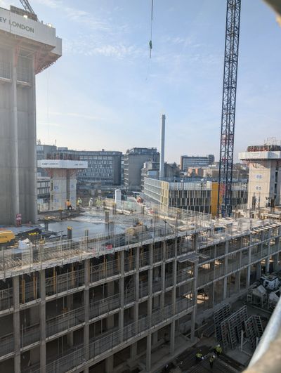 Construction site with workers and cranes under clear sky in an urban area.