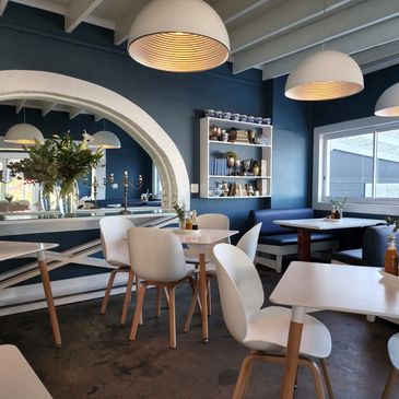 Modern cafe interior with white chairs and blue walls.