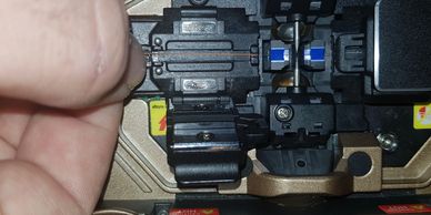 Close-up of a hand adjusting a small mechanical component with screws and connectors.