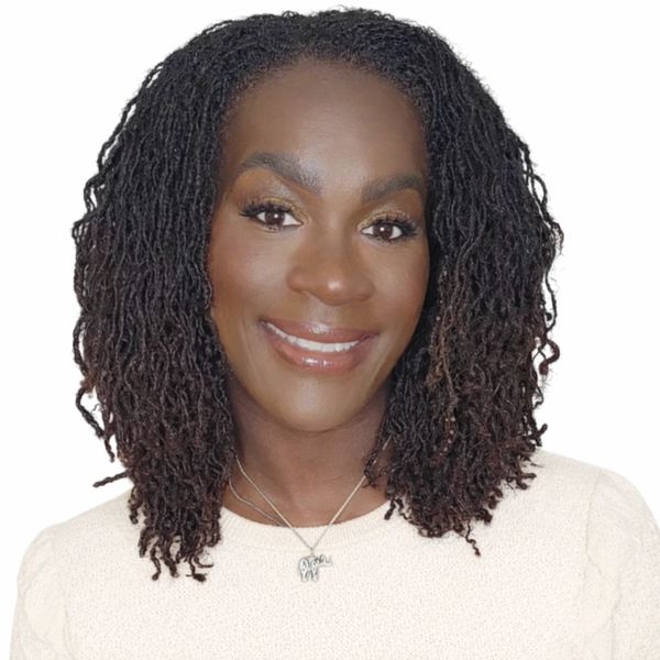 Smiling woman with natural curly hair wearing a cream sweater and a silver necklace.