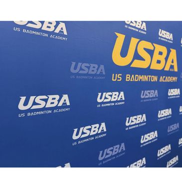 Backdrop with US Badminton Academy logos in blue and yellow.