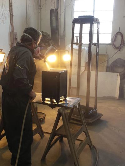 A person spray painting a small cabinet in a workshop.