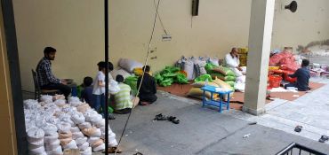 People sorting and packing bags of food inside a building.