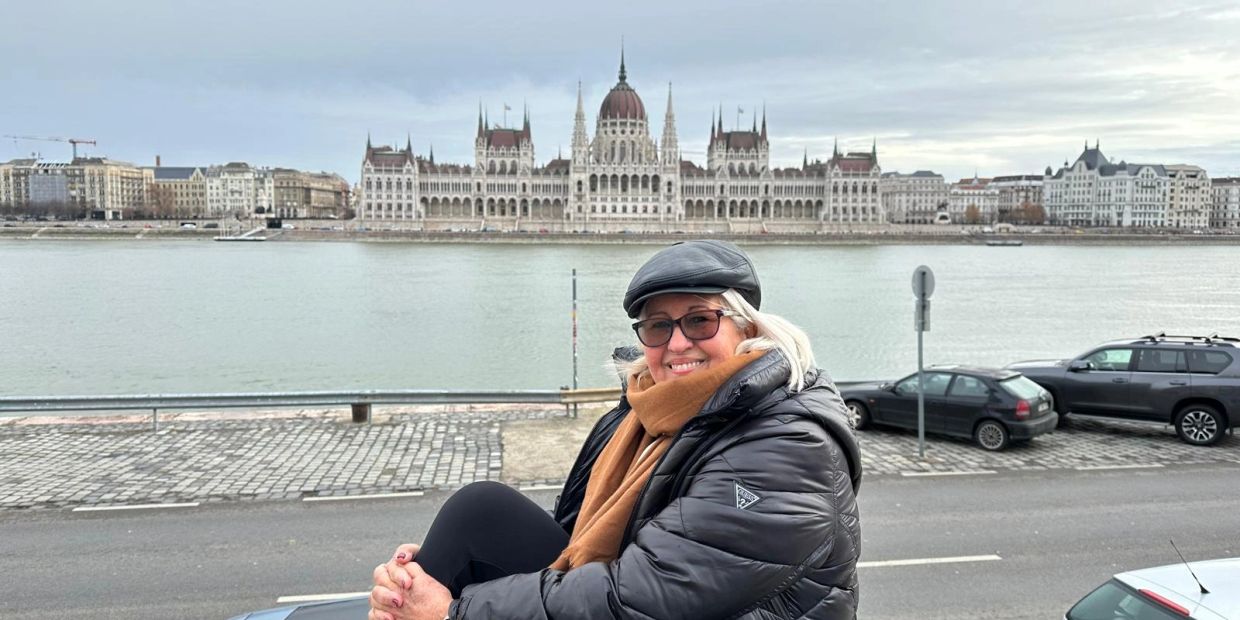 Woman smiling with Budapest Parliament in the background.