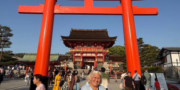 Tourists visit a large red torii gate at a Japanese shrine.