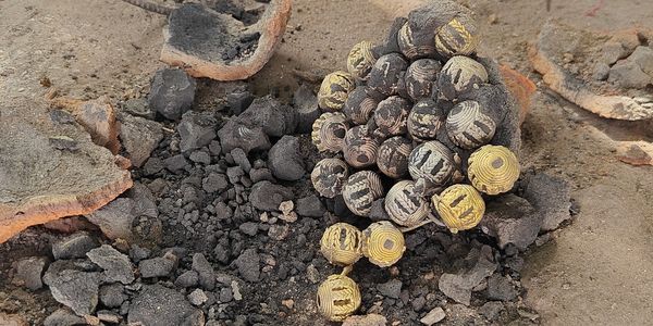 Group of brass beads surrounded by the broken mould.