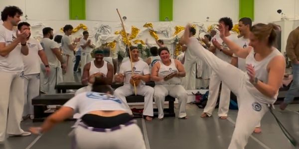 People practicing capoeira in a lively group setting indoors.