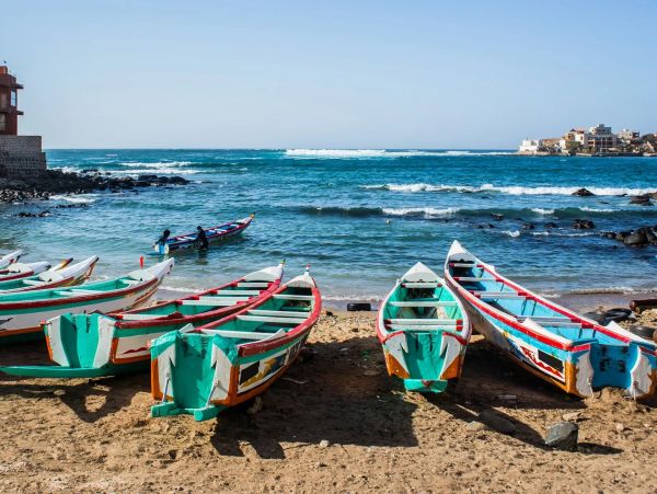 Colorful boats on a sandy beach with blue ocean.