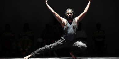 Man dancing with arms raised in spotlight.