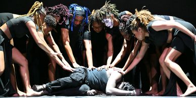 Dancers surrounding a person lying on the floor.