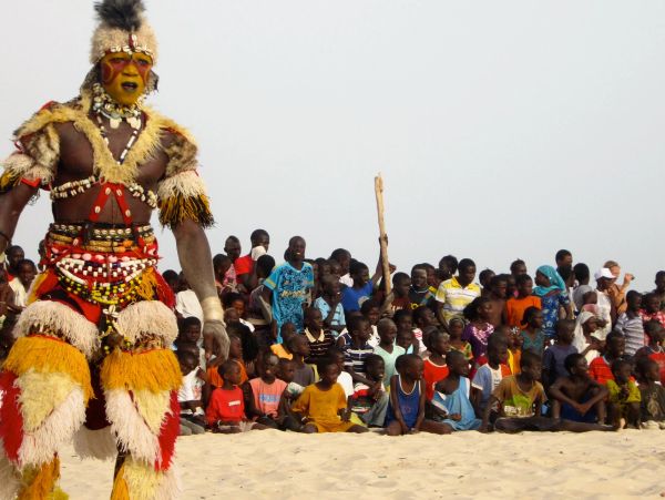 Man in traditional costume with crowd watching.