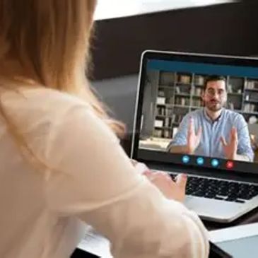 Woman video chatting with man on laptop.