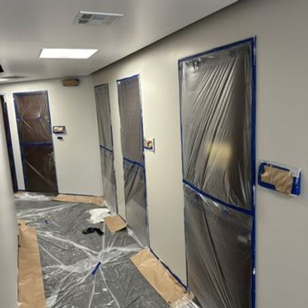 Hallway under renovation with plastic coverings and taped walls.