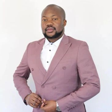 Man in mauve suit buttoning jacket.