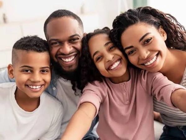 Happy family of four smiling and posing for a selfie together.