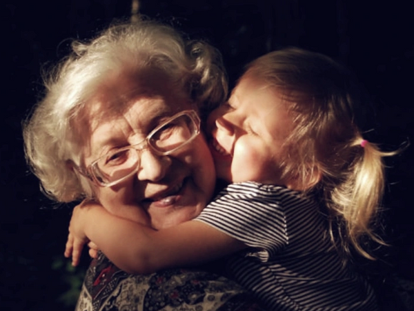 A toddler hugs her smiling grandmother warmly in a touching moment.