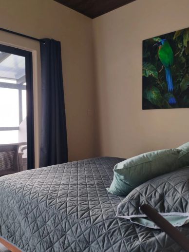 Habitación con cama y cuadro de ave verde.