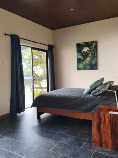 Dormitorio moderno con cama y cuadro de perezoso.