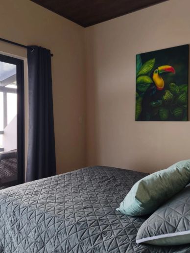 Habitación con cama y cuadro de tucán.