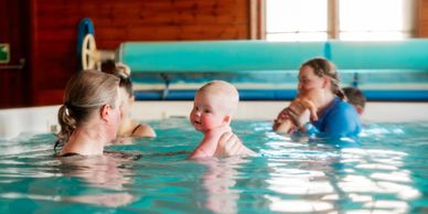 Mother and baby enjoying a swim in an indoor pool.