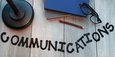 communications spelled out in letters with a lamp, two marketing books, eye glasses and pen