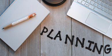 planning spelled out in letters with a laptop, pen, lamp and marketing book
