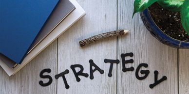 strategy spelled out in letters with marketing books, plant and a pencil
