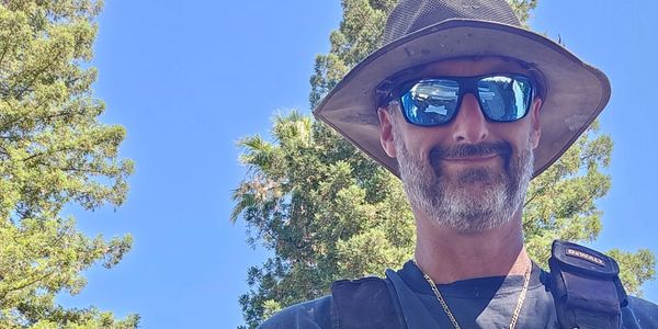 Man wearing sunglasses and a hat outdoors.