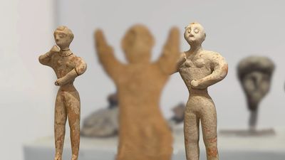 Two ancient figurines with raised arms and detailed features.