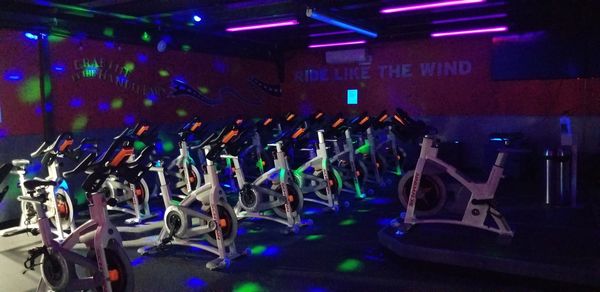 Dimly lit room with stationary bikes and colorful lights.