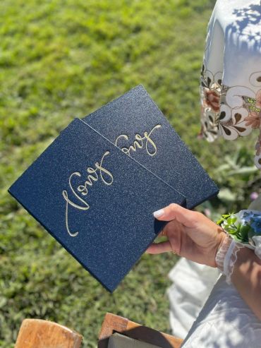 Two glittery black boards with gold cursive writing held outdoors.