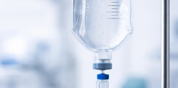 Close-up of an IV drip bottle filled with clear liquid in a medical setting.