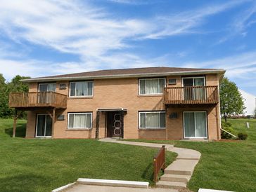 Two-story brick apartment building with balconies and green lawn.