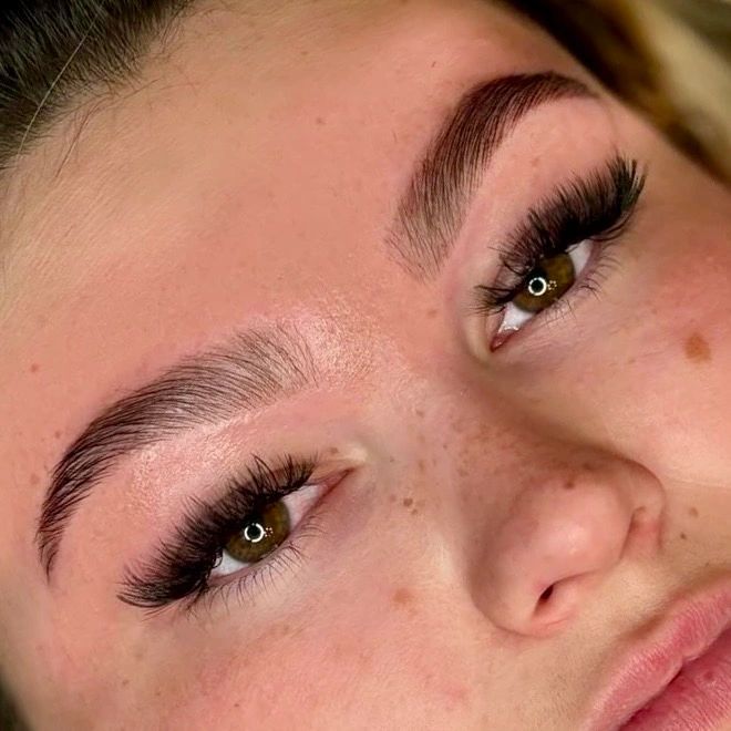 Close-up of a face highlighting thick eyelashes and well-groomed eyebrows.