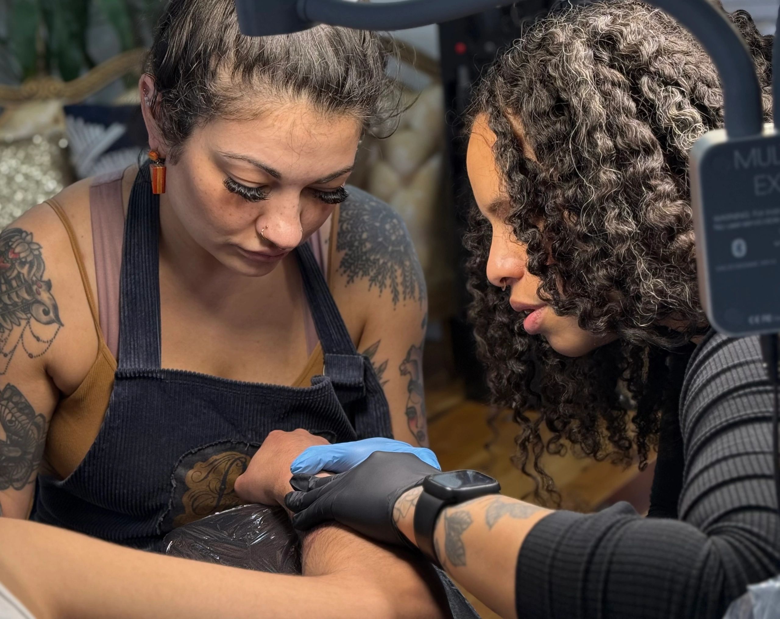 A tattoo artist intensely focused while working on a client's tattoo.