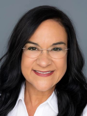 Smiling woman with glasses and dark hair.
