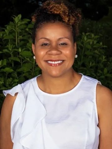 Smiling woman in white top outdoors.