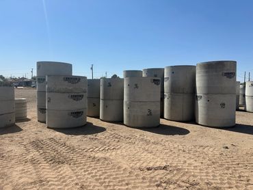 Large concrete pipes stacked in an outdoor yard.