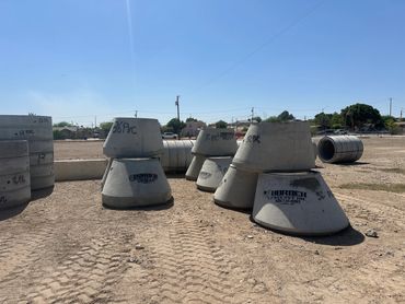Concrete manholes on a construction site under clear skies.