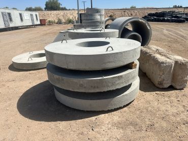 Stacks of concrete rings and pipes at a construction site.