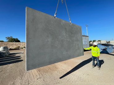 Worker guiding a large concrete slab suspended in the air.
