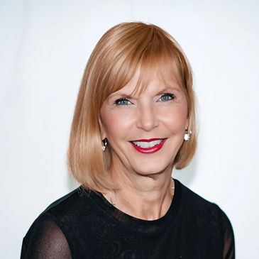 Smiling woman with blonde hair and red lipstick against a white background.