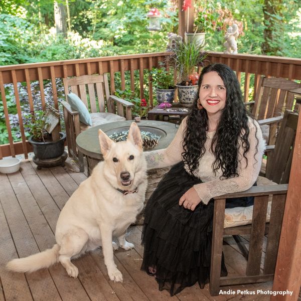 Woman sitting outside on a deck with a white German shepherd sitting next to her