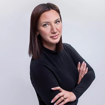 Confident woman with crossed arms in black top against plain background.