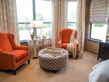 Custom window drapery panels and Roman shade with band treatment. Orange club chairs with purple sea