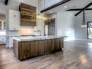 Wood floors, white shaker cabinets, black light chandelier, and white walls with gold faucet  