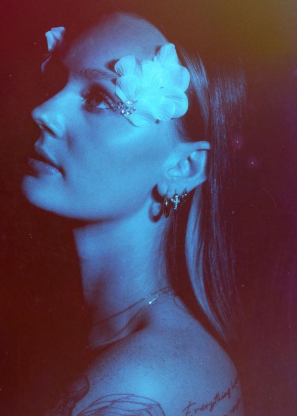 Portrait of a woman with flowers on her face in blue lighting.